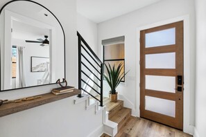 A staircase with a black railing, a wooden door with frosted glass panels, and a potted plant on the landing.