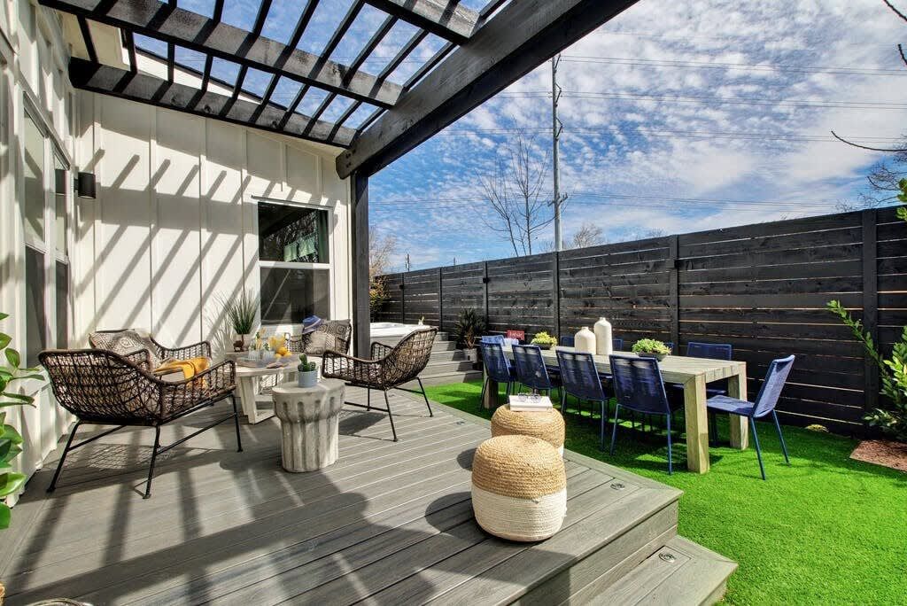 En udendørs terrasse med træterrasse, siddeområde og et bord med stole.
