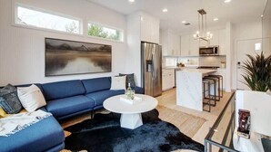 Un salon moderne avec un canapé bleu, une table basse blanche et un tapis noir.