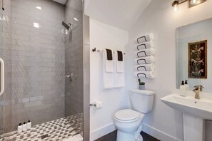A modern bathroom with a glass shower enclosure, a toilet, and a sink. - Modern Construction with Private Hot Tub (Austin)