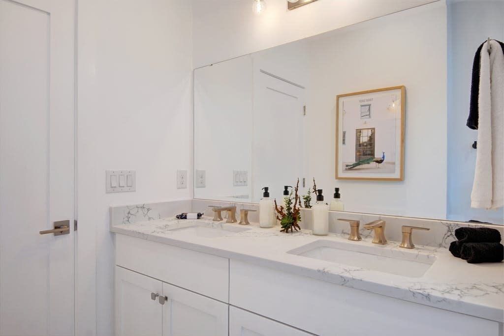 Une salle de bain moderne avec un grand miroir, deux vasques et un plan de toilette en marbre.