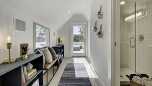 Un intérieur moderne avec un long couloir menant à une porte vitrée, un banc intégré et un espace douche.