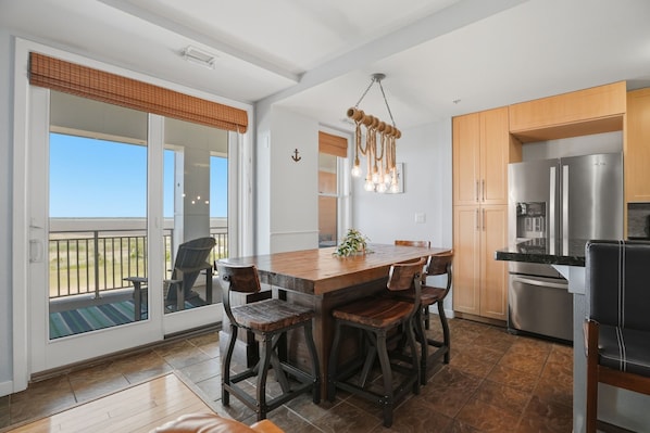A kitchen with a large island, wooden cabinets, and a stainless steel refrigerator.