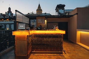Un bar en la azotea con vistas a la ciudad, un letrero que dice 'KHAI' y una estructura grande e iluminada.