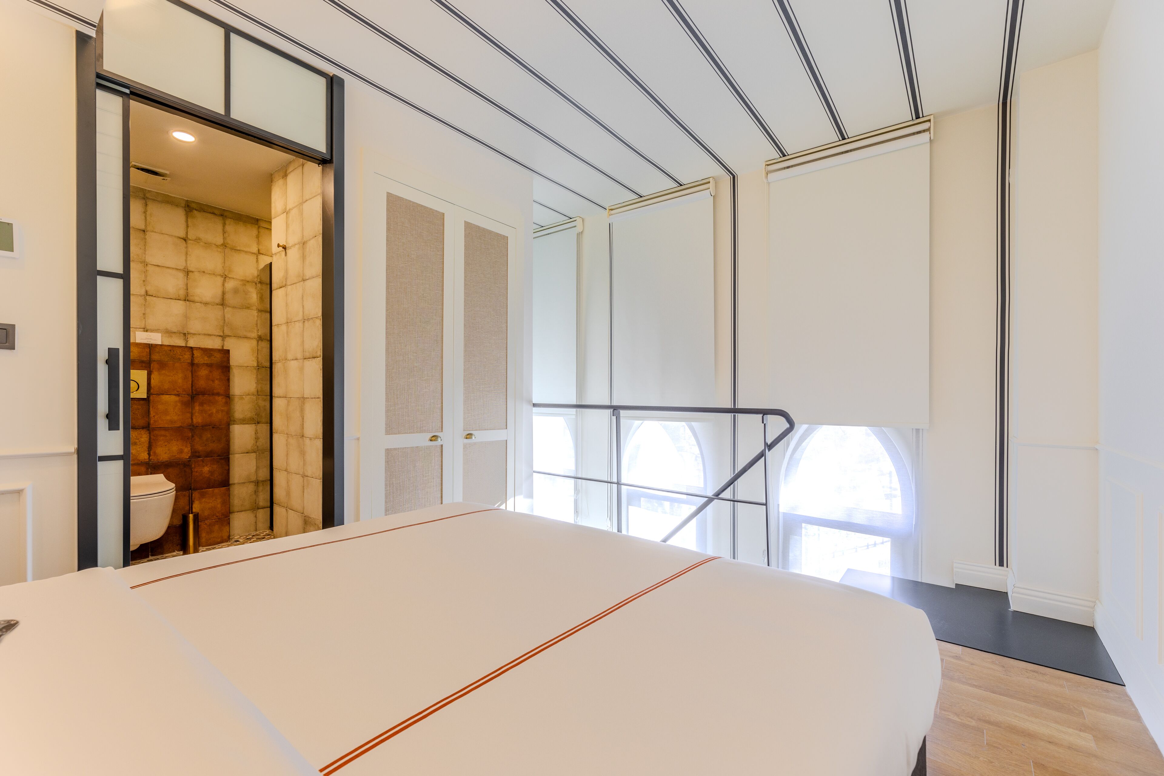 Une chambre d’hôtel moderne dotée d’un grand lit, d’une salle de bain avec douche et offrant une vue sur la ville par la fenêtre.
