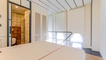 Une chambre d’hôtel moderne dotée d’un grand lit, d’une salle de bain avec douche et offrant une vue sur la ville par la fenêtre.