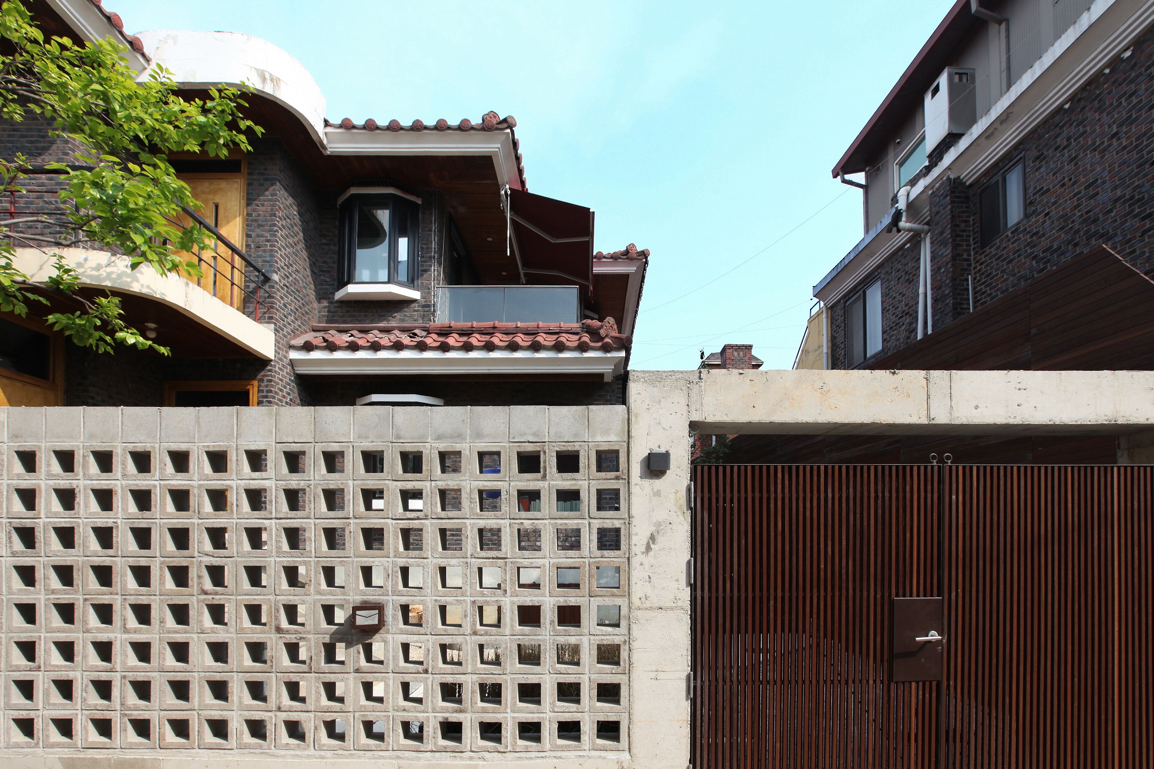 A residential building with a gated entrance, a balcony with a railing, and a window with a bell.
