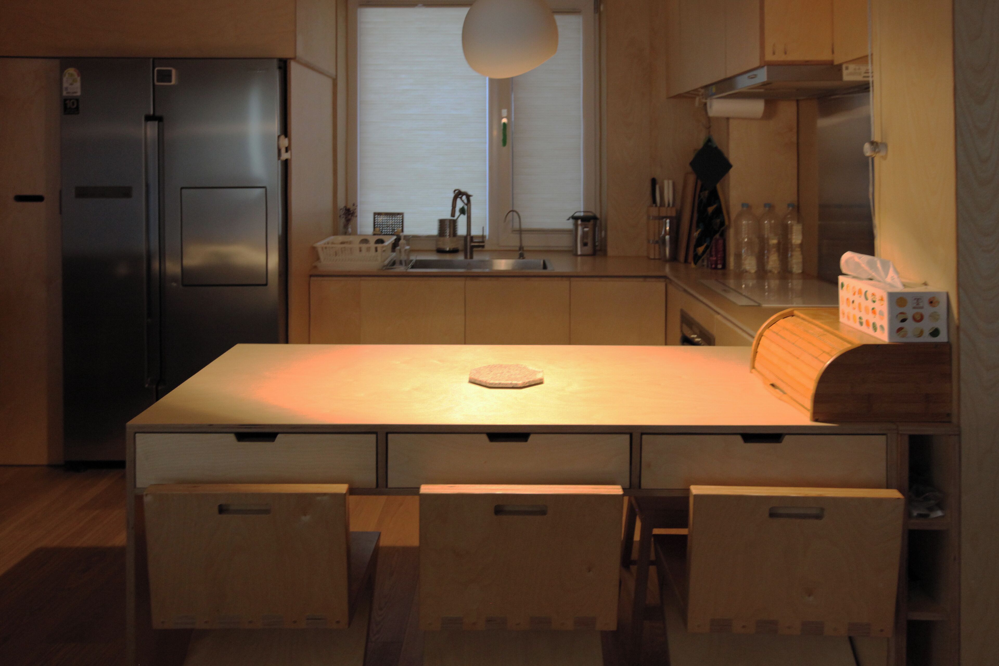 A modern kitchen with a central island, stainless steel appliances, and wooden cabinetry.