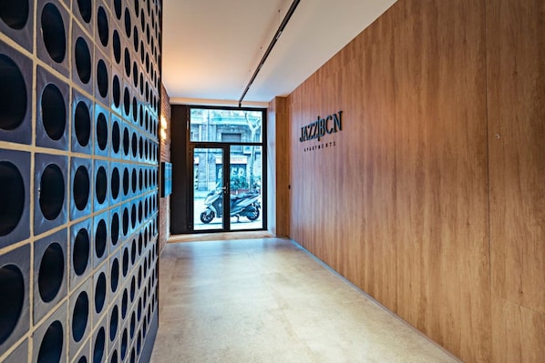 A hallway with a wooden wall and a sign reading 'JAZZBCN APARTMENTS'.