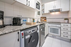 A compact kitchen with a dishwasher, oven, and coffee maker.