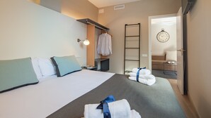 Ein Hotelzimmer mit Bett, Nachttisch, Lampe, Handtuchhalter und einer Tür zu einem Badezimmer.