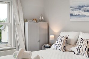 A hotel room with a bed, a nightstand, a lamp, a cabinet, and a window with curtains.