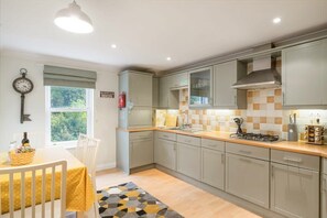 A modern kitchen with grey cabinets, a tiled backsplash, and a gas stove.