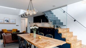 A modern kitchen with a glass staircase, a dining area with a wooden table, and a living room with a sofa and cushions. - Stylish Cambridge 1-bed Home with free parking (Cambridge)