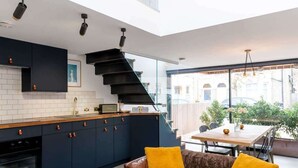 A modern kitchen with dark cabinets, a wooden countertop, and a built-in oven. - Stylish Cambridge 1-bed Home with free parking (Cambridge)