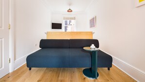 Et moderne værelse med en mørkeblå sofa, et lille rundt bord og en træsenggavl.