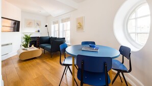 A modern living room with a round blue table, black chairs, a blue sofa, and a fireplace. - Calm Leicester Sq 1BR (London)