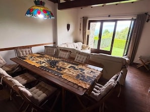 A dining area with a long table, cushioned chairs, and a stained glass light fixture. - Townhouse 3 rooms Fireplace, Garden, BBQ, Views & Wi-Fi (Alp)