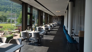 A modern restaurant with a long counter, large windows, and a view of a green landscape. - Boutique Hotel Moselgarten (Bullay)