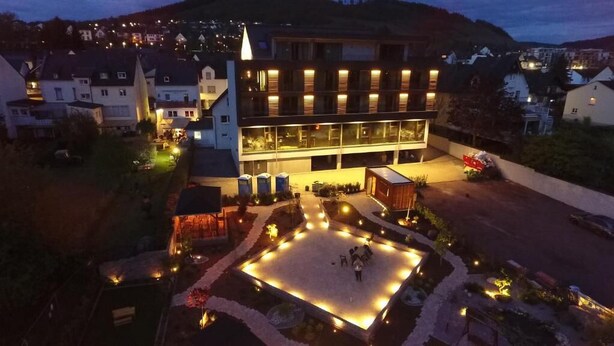 A hotel with a central courtyard, multiple floors, and a surrounding landscape. - Boutique Hotel Moselgarten (Bullay)