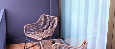 A balcony with two wicker chairs and a wooden floor.