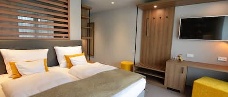 Una habitación de hotel moderna con una cama grande, un televisor montado en la pared y un armario de madera.