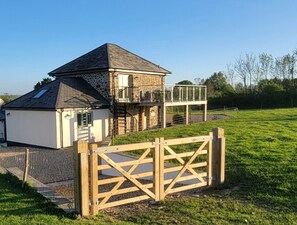 Een gebouw van steen en wit, met een balkon, een houten poort en een grasveld.