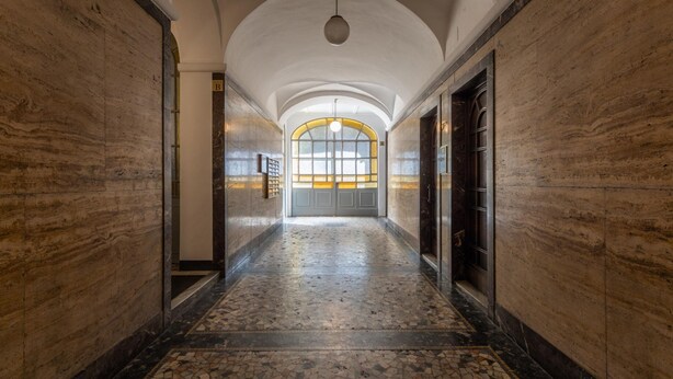 A corridor with a tiled floor, arched ceiling, and a large window with a yellow frame. - Quartieri Central Home by Wonderful Italy (Turin)