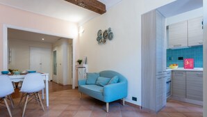A modern kitchen with white cabinets, a blue tiled backsplash, and a dining area with a white table and chairs. - Quartieri Central Home by Wonderful Italy (Turin)