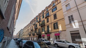 A narrow street lined with multi-story buildings, some with balconies and storefronts. - Quartieri Central Home by Wonderful Italy (Turin)