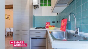 A modern kitchen with a gas stove, dishwasher, and a sink. There is a bowl of fruit on the counter and a red sign with text. - Quartieri Central Home by Wonderful Italy (Turin)