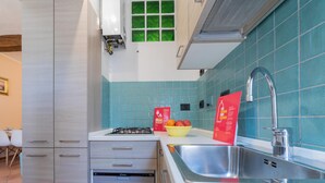 A modern kitchen with a gas stove, dishwasher, and a sink. There is a bowl of fruit on the counter and a red sign with text.