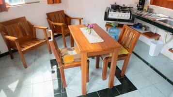 A compact kitchen with a dining area, including wooden furniture and a tiled floor.