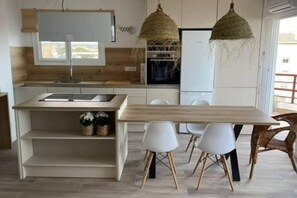 A modern kitchen with a wooden countertop, white cabinets, and a dining area with a wooden table and white chairs.