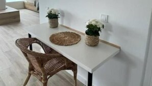 Una habitación moderna con una mesa blanca, una silla de mimbre y un espejo grande en la pared.
