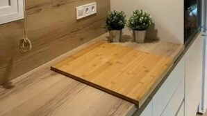 Una cocina moderna con encimera de madera, una lámpara de pared y dos plantas en macetas.