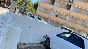 Un coche blanco aparcado junto a una pared de hormigón con una línea amarilla.