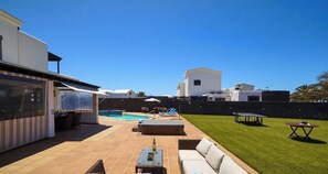 Eine moderne Außenpatio mit Pool, Liegestühlen und Esstisch.