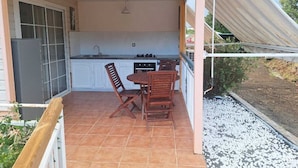 A covered patio with a kitchen area, including a dining table and chairs, and a refrigerator. - A quiet gîte in the heart of nature (Lamentin)