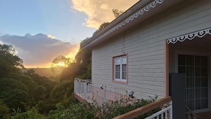 A house with a balcony overlooking a lush, green landscape during sunset. - A quiet gîte in the heart of nature (Lamentin)