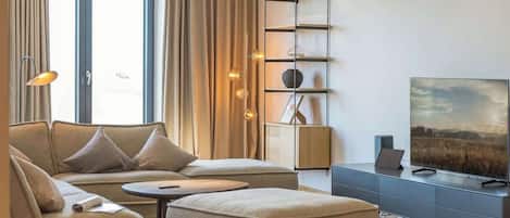 Een moderne woonkamer met een bank, een voetenbankje en een televisie op een meubel.