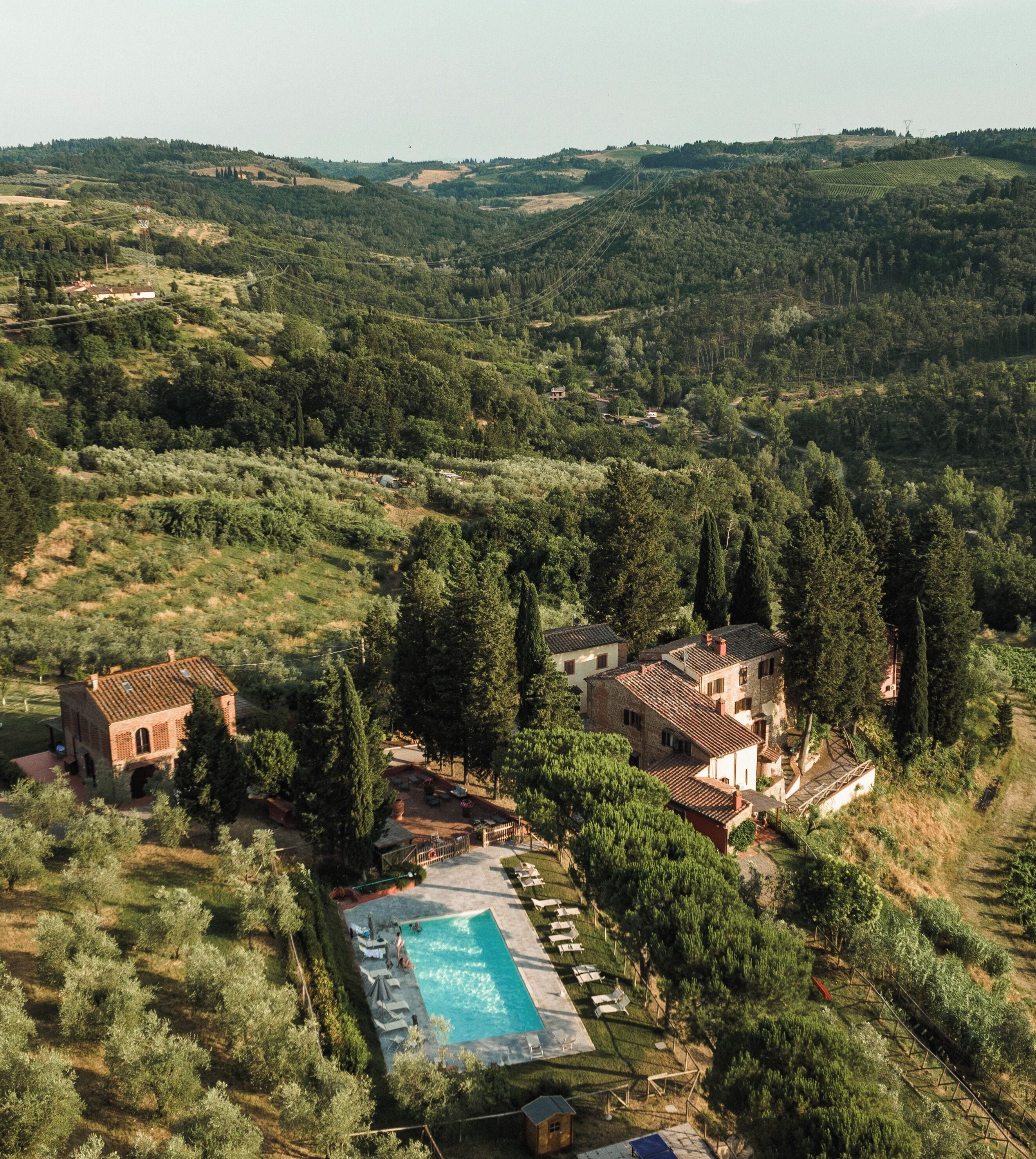 A villa with a swimming pool surrounded by trees and hills.