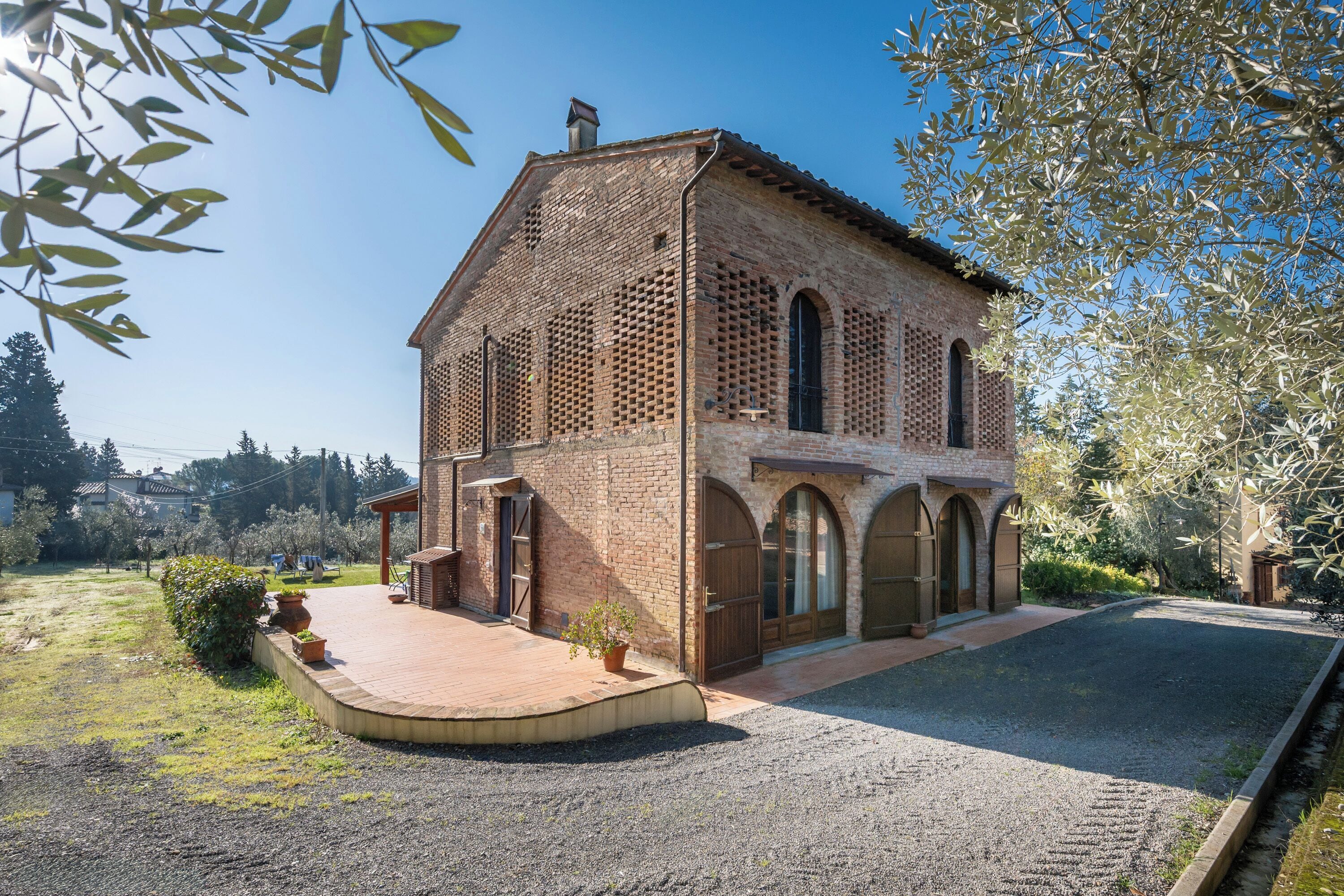 A two-story brick building with a courtyard, arched windows, and a gravel driveway.