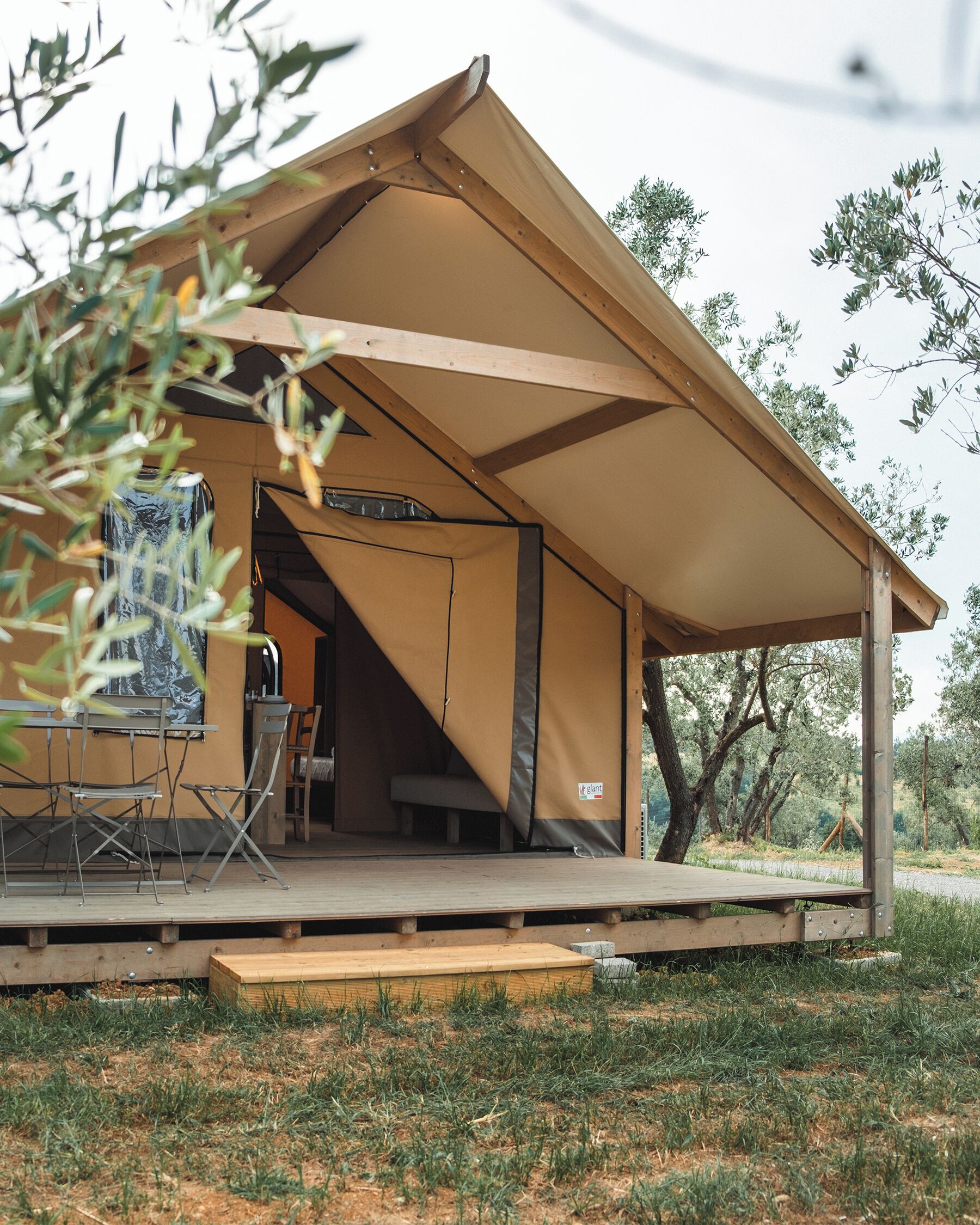 A tent with a flat roof and a wooden deck, surrounded by trees.