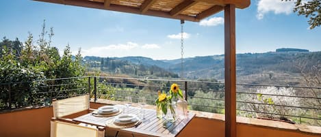 An outdoor dining area with a table set for two, overlooking a scenic valley.