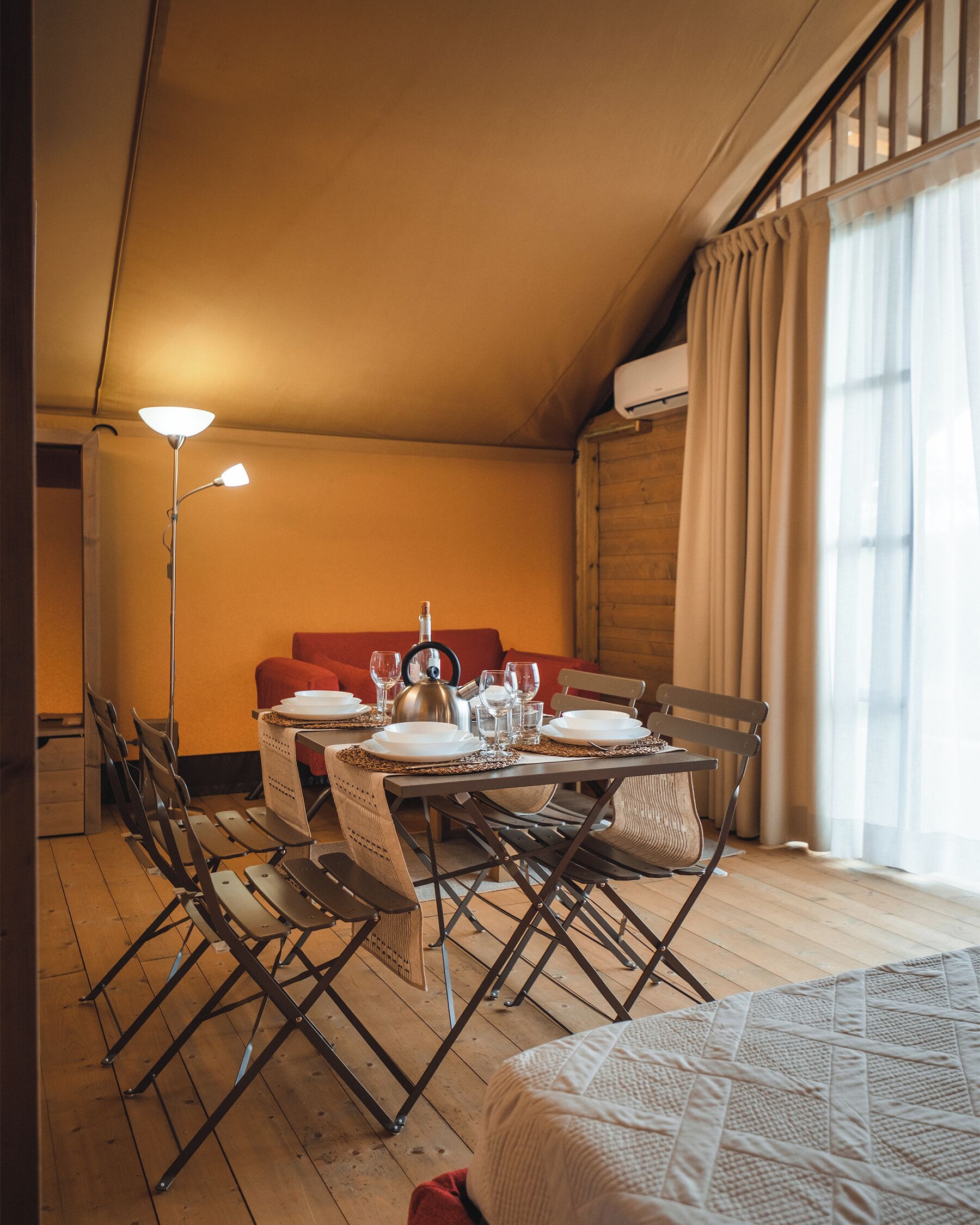A cozy room with a dining table set for four, a sofa, and a bed.