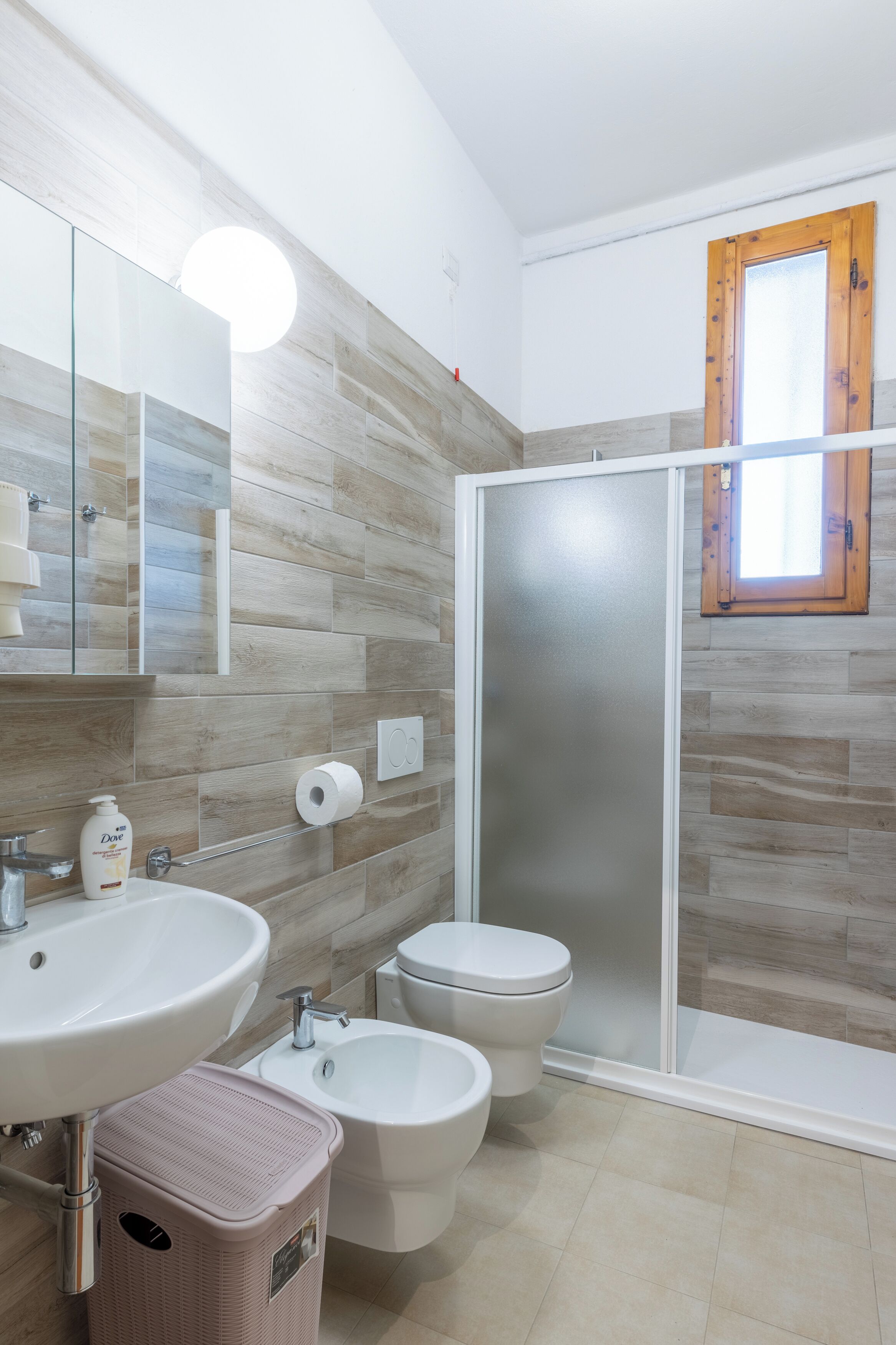 A bathroom with a sink, bidet, toilet, and a glass shower enclosure.