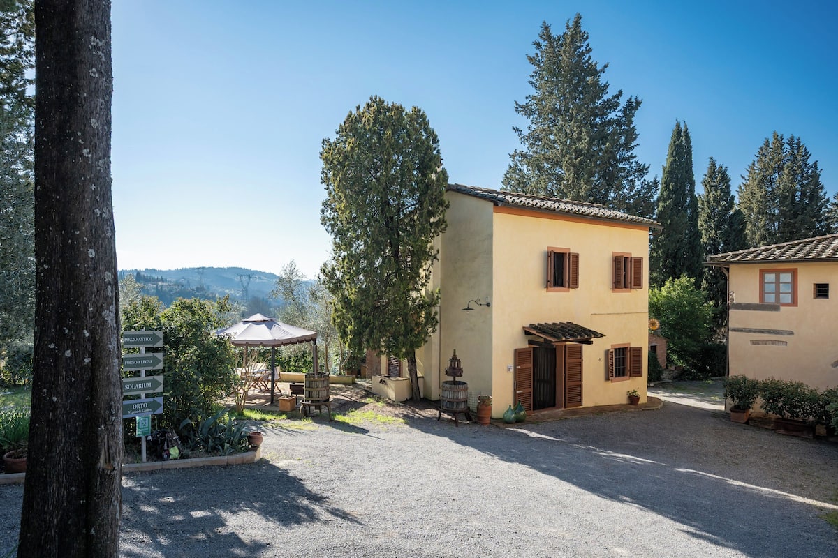 Eine Villa mit Kiesauffahrt, einer Terrasse mit Gartenmöbeln und einem Wegweiser mit Beschilderung.