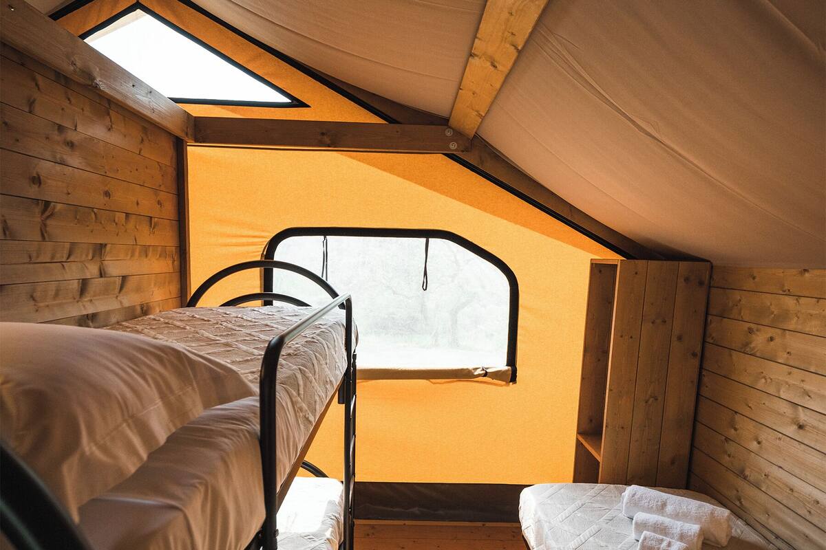 Ein Schlafsaalzimmer mit Etagenbetten, einem Oberlicht und Holzwänden.