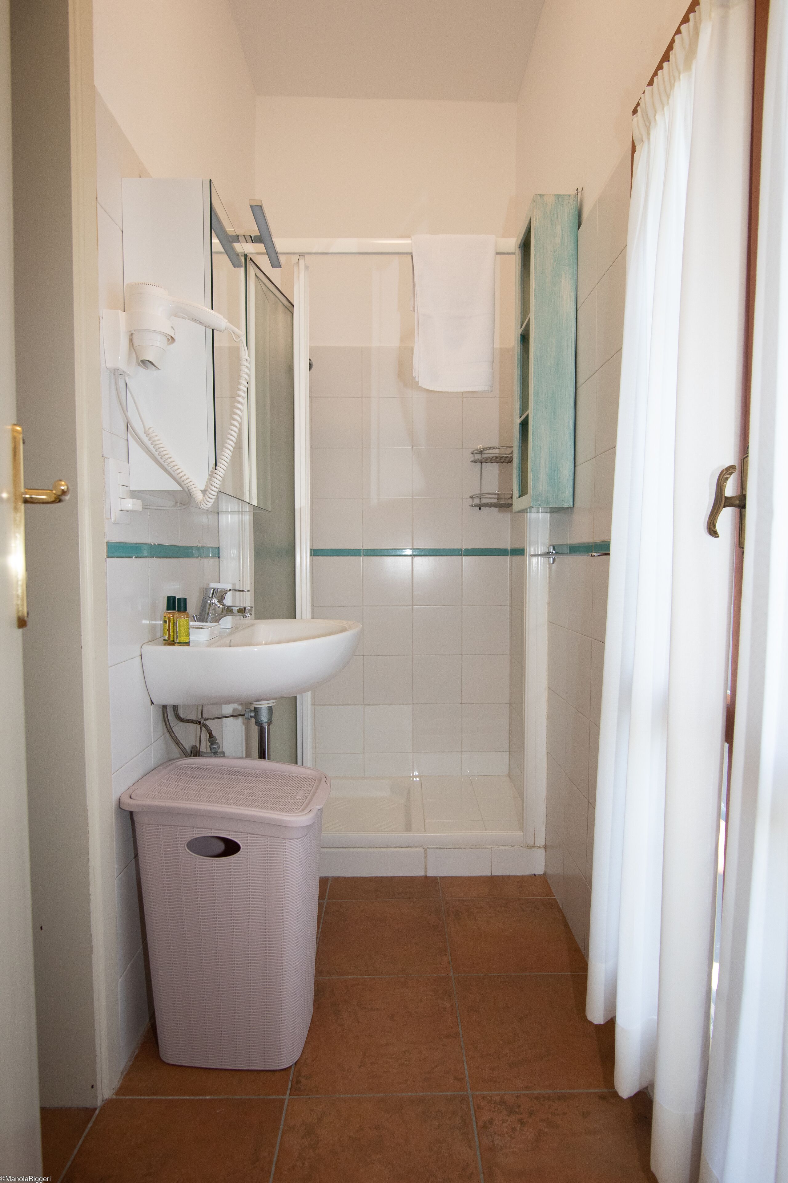 Une salle de bain avec une douche, un lavabo et une poubelle.